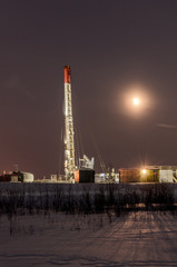 Obraz premium Oil rig during moon eclipse in the oilfield. Winter period. Oil and gas concept. Toned.