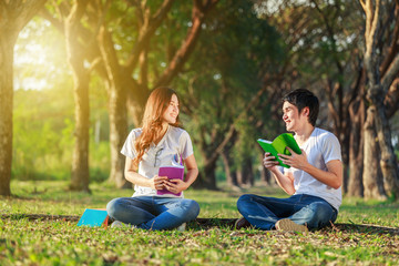 man and woman sitting and reading a book in park