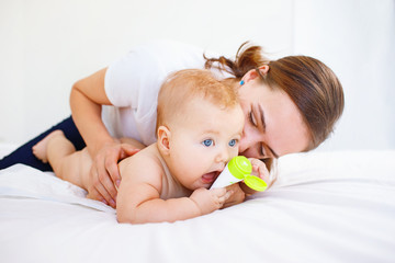 Mother kissing her baby on bed