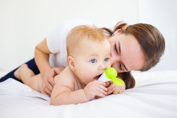 Mother playing with her baby on bed