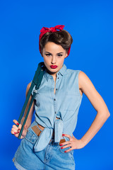 fashionable young woman in pin up style clothing with wrench isolated on blue