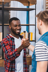 Fototapeta premium cropped shot of young multiethnic men holding hands and smiling each other