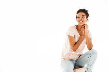 Obraz premium Portrait of beautiful woman sitting on chair and looking aside on copyspace with smile, isolated over white background