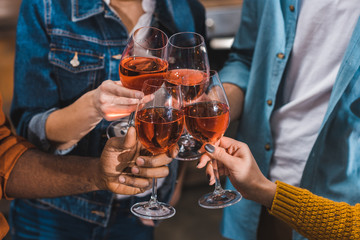 close-up partial cropped of friends clinking wine glasses together