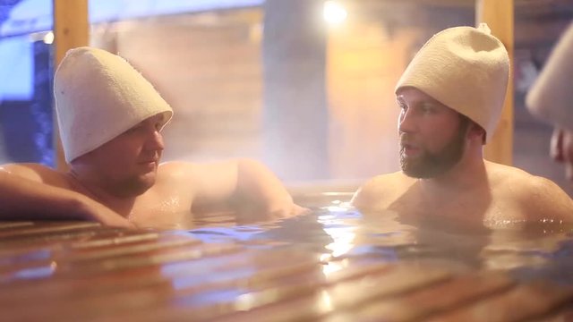 three men relax in outdoor hot tub Jacuzzi bath in winter