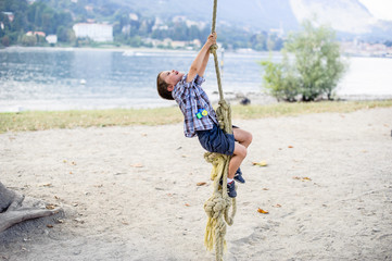 child boy climbs on a big rope in the outdoor