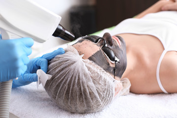 Young woman undergoing carbon peeling procedure in salon