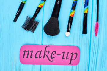 Set of brushes for make up. Fashion design makeup brushes. Pink paper card, blue wooden background. Equipment for applying make up.