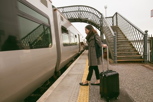 Woman getting in the train with luggage