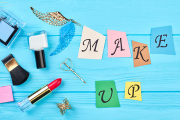 Colorful paper letters make up. Set of cosmetics items and accesories on wooden background. Girl makeup objects and jewelry.