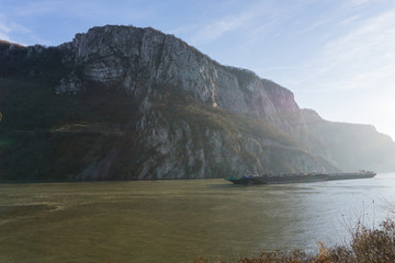 Large barges entering the Danube gorge in the evening
