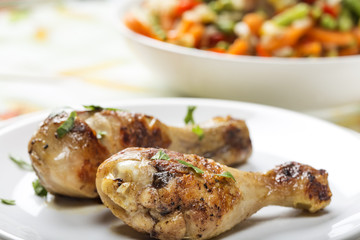 Two grilled chicken drumsticks with parsley on palte
