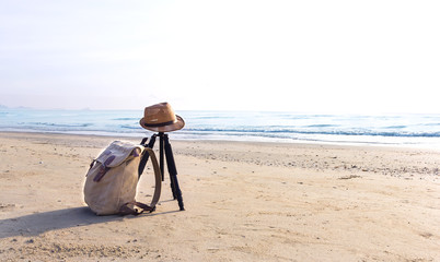 View of the sandy beach with a brown hat and knapsack on the beach near the sea. © Pongsak