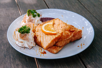 Beautiful French toast dish with orange honey sauce, strawberry jam, on old wooden table