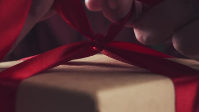 young man hands tying ribbon bow on present box