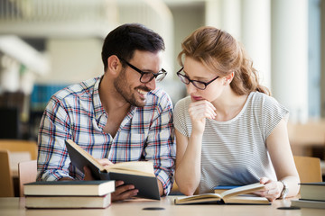 Happy students couple in school library have discussion