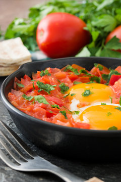 Shakshuka in iron frying pan on wooden table. Typical food in Israel.