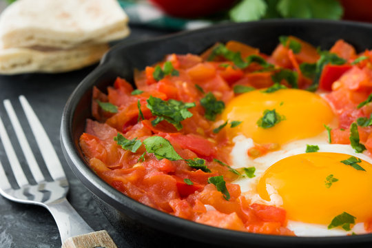 Shakshuka in iron frying pan on wooden table. Typical food in Israel.