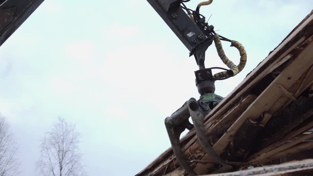 Crane arm loader unloads wood scraps from heavy truck at sawmill production, cold cloudy winter day