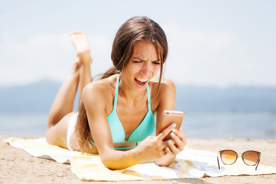 surprised girl with phone on a beach