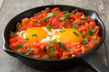Shakshuka in iron frying pan on wooden table. Typical food in Israel.