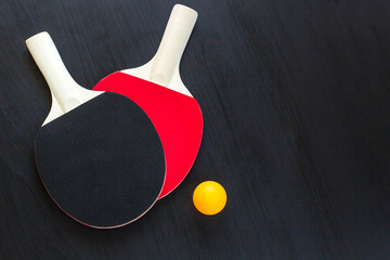 Two table tennis or ping pong rackets and ball on a black background
