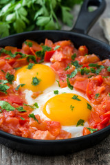 Shakshuka in iron frying pan on wooden table. Typical food in Israel.
