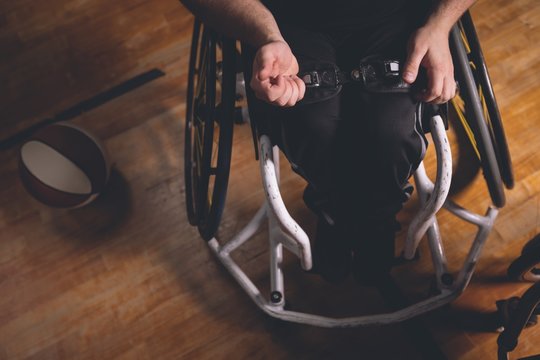 Disabled man adjusting belt of wheechair 