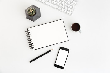 White desk, table with spiral notebook, coffee, cactus and smartphone screen for mock up or product monage. Flat lay.