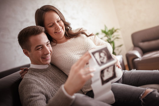 Young pregnant couple looking at ultrasound image