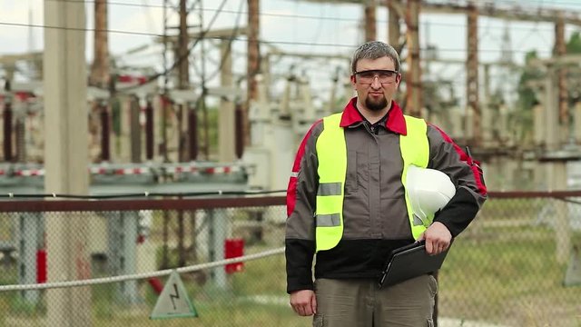 Worker on electric power station. Power engineering specialist in goggles and hard hat at heat power plant looks at the camera