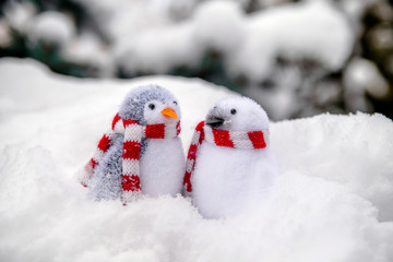 Two decorative penguins sit on the snow 