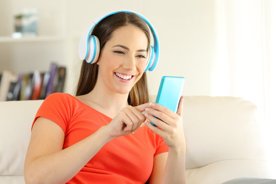 Girl listening to music with headphones and phone at home