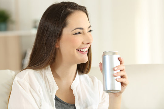 Female holding a soda can on a couch at home