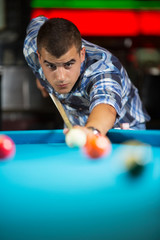 Young man at the pool table taking a shot