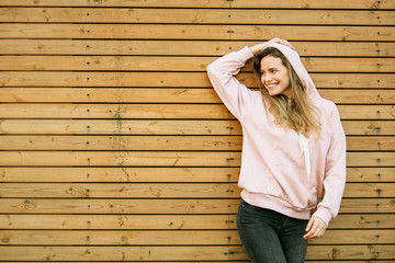 cool young woman in pink hoodie on wooden background - Powered by Adobe