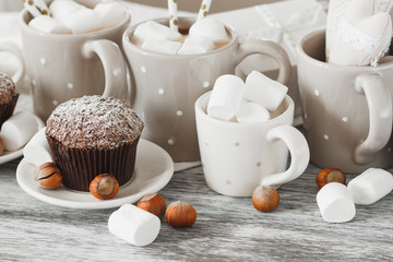 Cups with cacao and marshmallow, cupcakes and different decorations