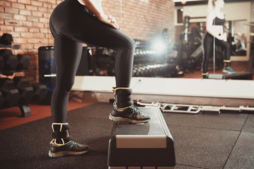 Girl steps foot on Step platform. Concept of aerobics, keeping in shape, exercises on buttocks