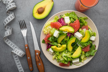 Fresh salad with avocado and grapefruit on a stone table