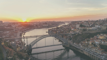 Aerial long exposure of the iconic Dom Luis I bridge at sunset designed by Gustav Eiffel crossing the Douro River,historical Ribeira and Se District in Porto,Portugal.Unesco World Heritage Site
