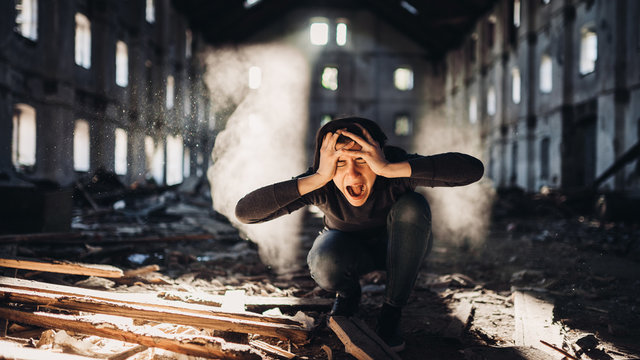Sad depressed person in abandoned destroyed building crying.Emotional portrait.Mentally ill woman with bipolar disorder and psychosis.Schizophrenia.Madness, crazy person.
