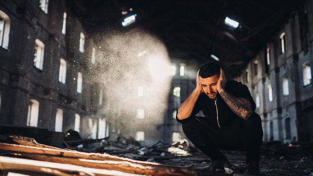 Sad depressed person in abandoned destroyed building crying.Emotional portrait.