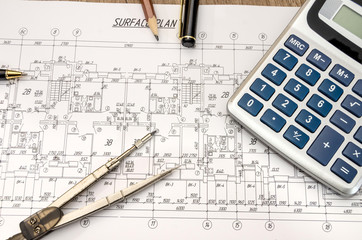 architectural construction documents with pen and calculator