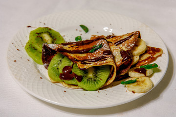 Pancakes with fruits, hot chocolate and powdered sugar