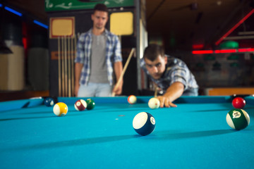 Below view of friends playing billiard in a pool hall