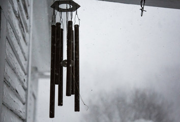 Desolate wind chimes swaying in the breeze of a snow storm in western New York. 