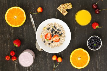Fototapeta na wymiar Healthy breakfast of muesli, berries with yogurt and orange juice on dark background.