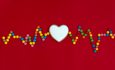 on a red background heart rhythm beats cookies with white mastic music waves radio song souls multi-colored round candies 