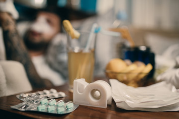 Young man recovering form rhinoplasty plastic aestetic nose surgery at home.Swelled face male in pain holding cold compress ice on bruises.Operated man healing process