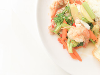 Fried Savory sauteed mixed vegetables with shimp and fried egg served with rice in white dish on white background as Thai homemade meal or recipe in the restaurant. Thai style food.